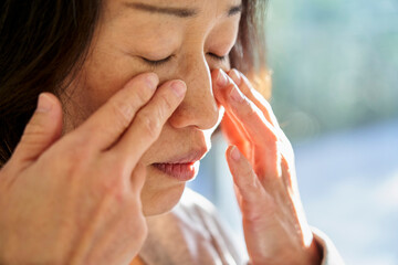 Close-up of senior Asian woman touching her face