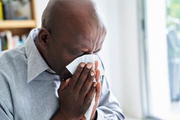 Close-up shot of senior African-American man with a cold blowing his nose