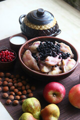 Ukrainian dumplings with blueberries. Still life with apples, candies, nuts.