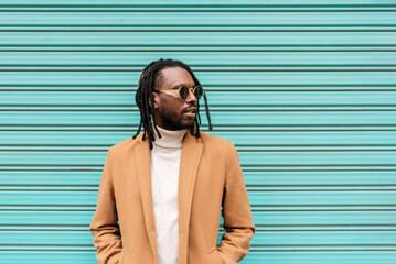 handsome african american man with braids wearing stylish sunglasses looking away while standing...
