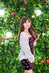 Portrait beautiful young asian woman red dress costume and Christmas greeting picture parcel decoration on Christmas tree light circular bokeh background Decoration During Christmas and New Year.