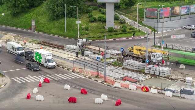 Loader crane for loading and unloading concrete plates from oversized truck with an extended loading platform which stands on a road construction site aerial timelapse