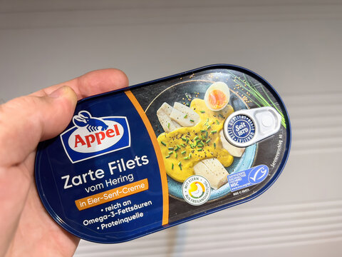 Frankfurt, Germany - Oct 8, 2022: POV male hand holding fish preserve can with Appel Zarte filets from Hering with eier senf egg mustard creme