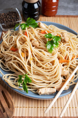Japanese wheat noodles with chicken and soy sauce on a blue plate and bamboo napkin.