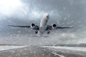 Fototapeta na wymiar Take off of an airliner in heavy snow and a blizzard at the airport of departure. The concept of bad weather, flight delays and cancellations.