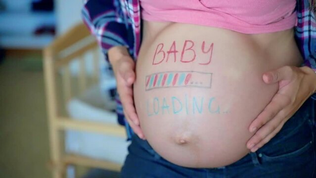 Pink and blue baby loading inscription on woman pregnant belly, mom caring and stroking her tummy with hands, happy mother ready for giving birth to her beloved baby child, unforgettable moments of