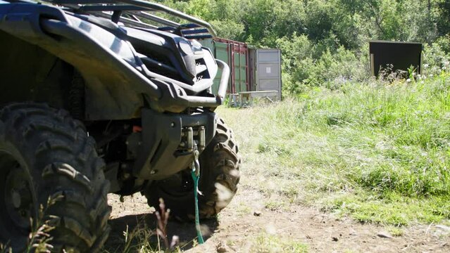 Front of all terrain 4x4 quadbike standing in grass field with containers in background