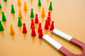 Horseshoe magnet attract red people from crowd on yellow background. Attracting target customer in...