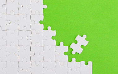 Unfinished white puzzle pieces on green background