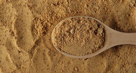 Unrefined brown cane sugar pile in wooden spoon background and texture