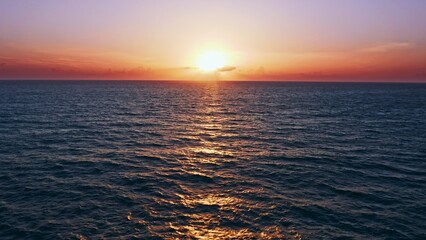 Aerial view over beautiful  ocean during  sunset. Top view to the ocean in summer day while sunset - closeup. Drone view of a Scenic slow motion ocean waves. Beautiful sunrise over ocean