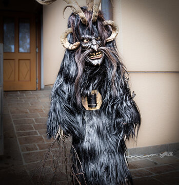 Portrait of a boy in a krampus costume, black goat skin, horns and a wooden mask, Austria, Salzburg