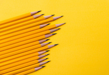 Fototapeta premium A row of yellow pencils on yellow background