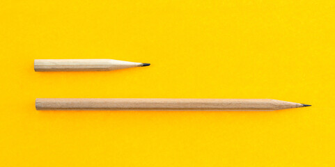 Long and short pencils on yellow background