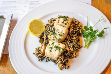 Baked sturgeon piece on quinoa with champignon, pea sprout and lemon