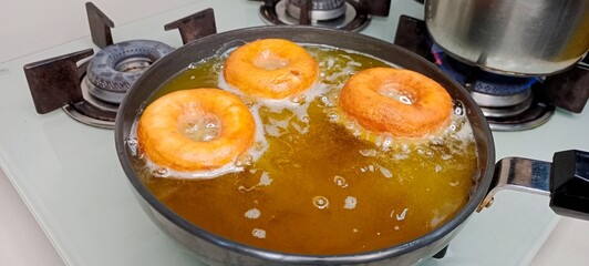 assorted donuts with chocolate frosted, pink glazed and sprinkles donuts. Donuts in hand or tray