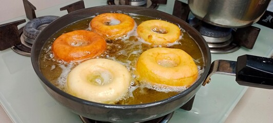 assorted donuts with chocolate frosted, pink glazed and sprinkles donuts. Donuts in hand or tray