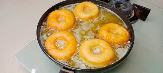 assorted donuts with chocolate frosted, pink glazed and sprinkles donuts. Donuts in hand or tray