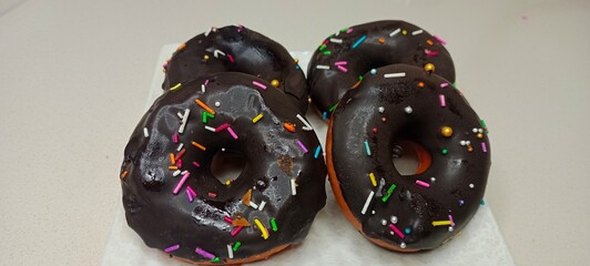 assorted donuts with chocolate frosted, pink glazed and sprinkles donuts. Donuts in hand or tray