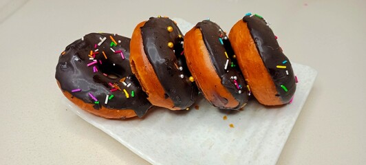 assorted donuts with chocolate frosted, pink glazed and sprinkles donuts. Donuts in hand or tray