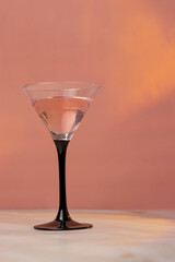 Pink cocktail in a tall triangular martini glass on a pink background