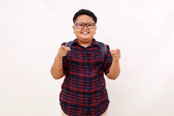 Happy asian school boy standing while pointing at the camera. Isolated on white background