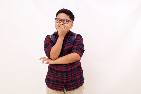 Happy asian school boy standing while glancing sideways. Isolated on white with copyspace
