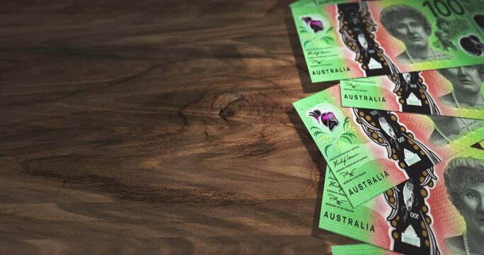 Australian Dollar 100 AUD banknotes on the wooden table. Australia currency paper notes 3D concept background. Seamless and looped.