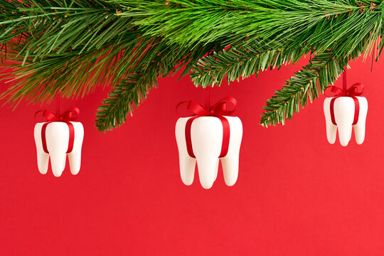 White teeth hanging on Christmas tree on a red background