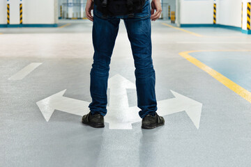 Man legs standing in front of three direction arrows