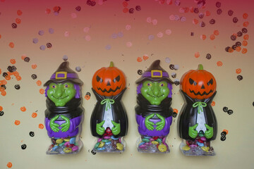 Terrible figures of witches and monsters on red background strewn with colorful confetti. The concept of the Halloween holiday. Festive figurines.