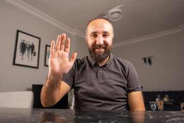 Wave hand to camera, caucasian bearded business man wave hand to camera. Web cam view portrait of smiling young caucasian male, video call concept. Smiling, happy and working from home meeting online.