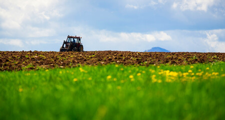 Green grass field and old small tractor plowing in the rural area of Transylvania, Romania.