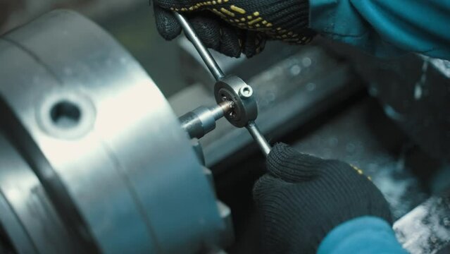 A worker cuts a thread in a metal part.