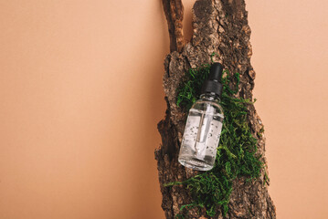 Cosmetic bottle with gel or other cosmetic product on bark with moss. Natural organic cosmetic. Beauty concept. Front view. Copy space
