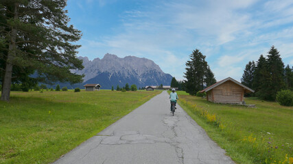 Fototapeta na wymiar Fahrradfahrerin auf dem Panorama Radweg bei den Buckelwiesen zwischen Krün und Mittenwald 