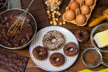 Preparing doughnuts at home. Ingredients for donuts such as eggs, milk, chocolate, pudding, butter, cacao, flour, rolling pin, cake pan, grater, egg beater, spatula