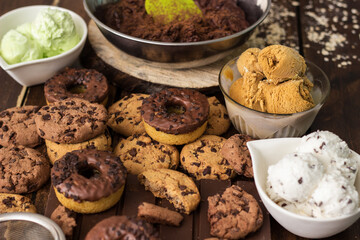 A sweet table containing ice cream, donuts and chocolate chip cookies