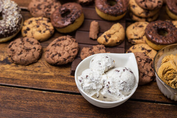 A sweet table containing ice cream, donuts and chocolate chip cookies