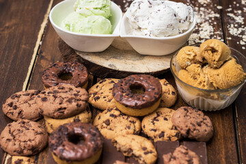 A sweet table containing ice cream, donuts and chocolate chip cookies