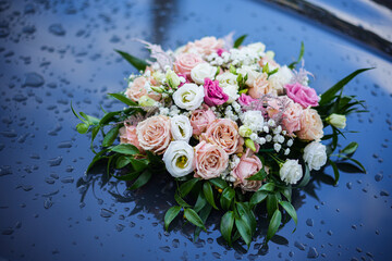 Obraz na płótnie Canvas Rose bouquet on a car hood, with rain drops
