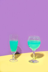 Two glasses of wine. The concept design of the celebration. Minimalistic trendy style. Yellow, Turquoise, Purple color.