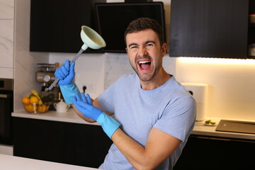 Man holding a plunger in his kitchen 