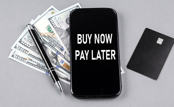 Credit card and text BUY NOW - PAY LATER on smartphone with dollars and pen. Business concept