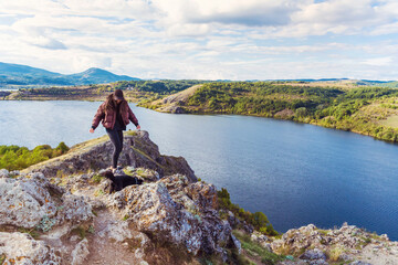 Fototapeta premium Traveler woman walking on a rocks high above a blue lake .Traveling in the autumn nature in Bulgaria . Pchelina Lake 