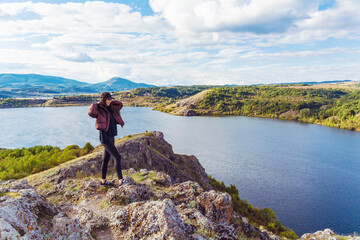 Fototapeta na wymiar Traveler woman walking on a rocks high above a blue lake .Traveling in the autumn nature in Bulgaria . Pchelina Lake 