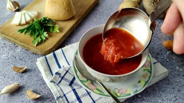 The chef pours borscht into a white plate.  Ukrainian traditional soup.  Borscht 