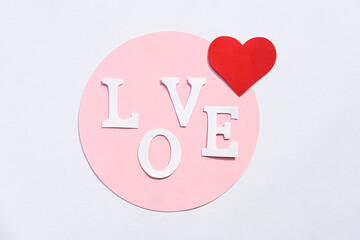 The word love from paper letters and red hearts on a white background. Flat lay, place for text. Valentine's day background.