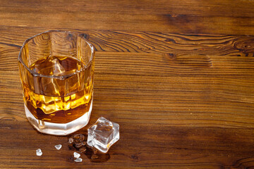 Glass of golden whiskey with ice. Strong alcoholic drink background