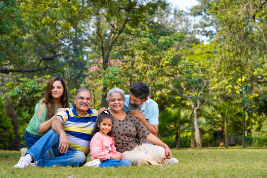 Happy indian or asian family sitting at park.